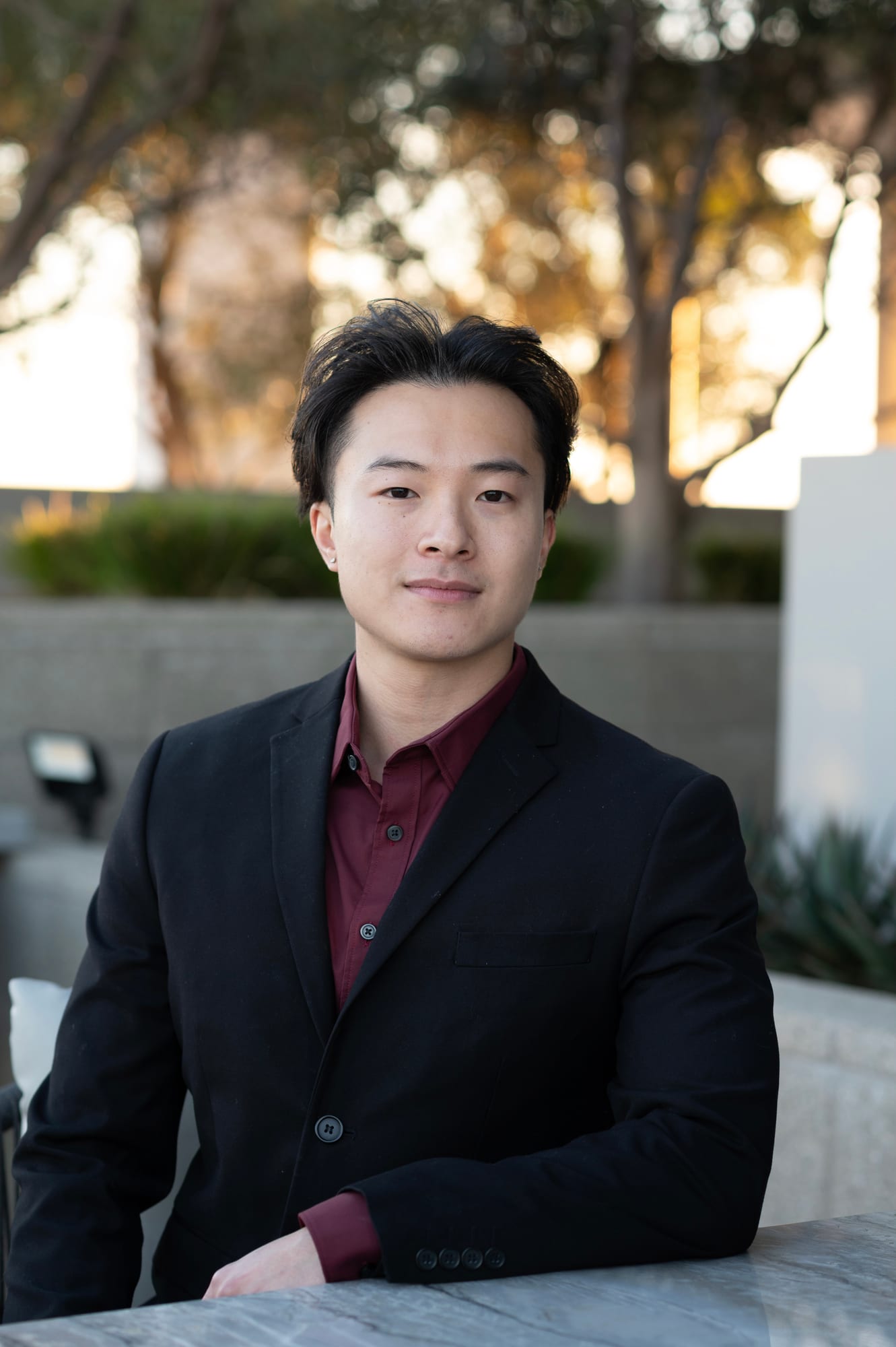 John Wen in a black suit and burgundy shirt